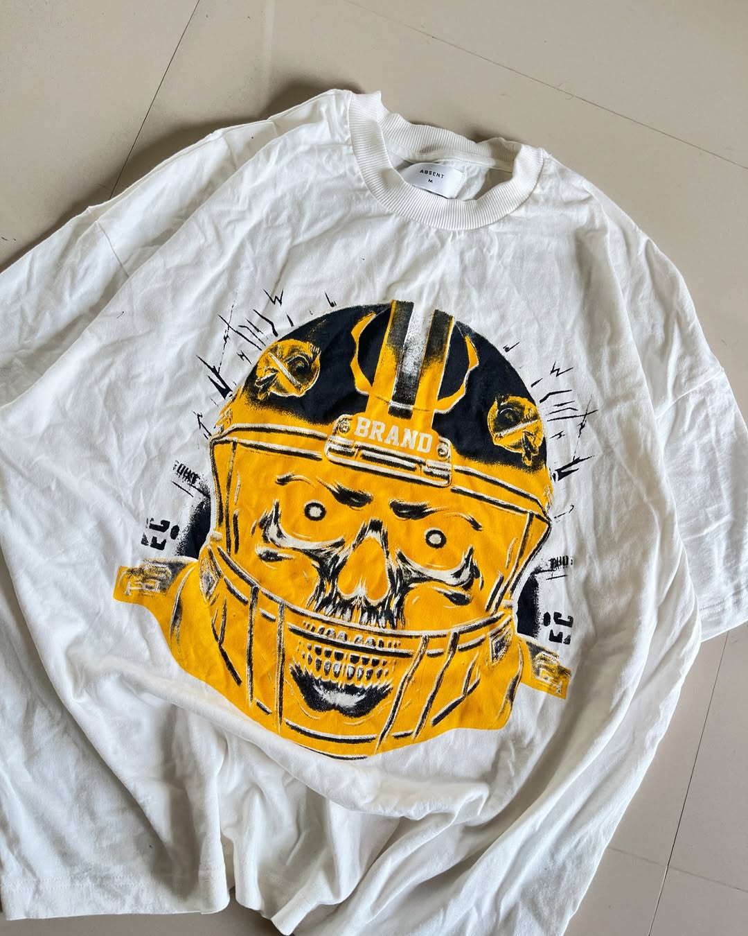 White oversized t-shirt featuring yellow football helmet and skull fusion graphic from Junk Fits