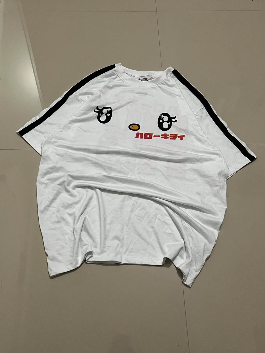 White oversized tee with cartoon eyes, Japanese text, and black sleeve stripes