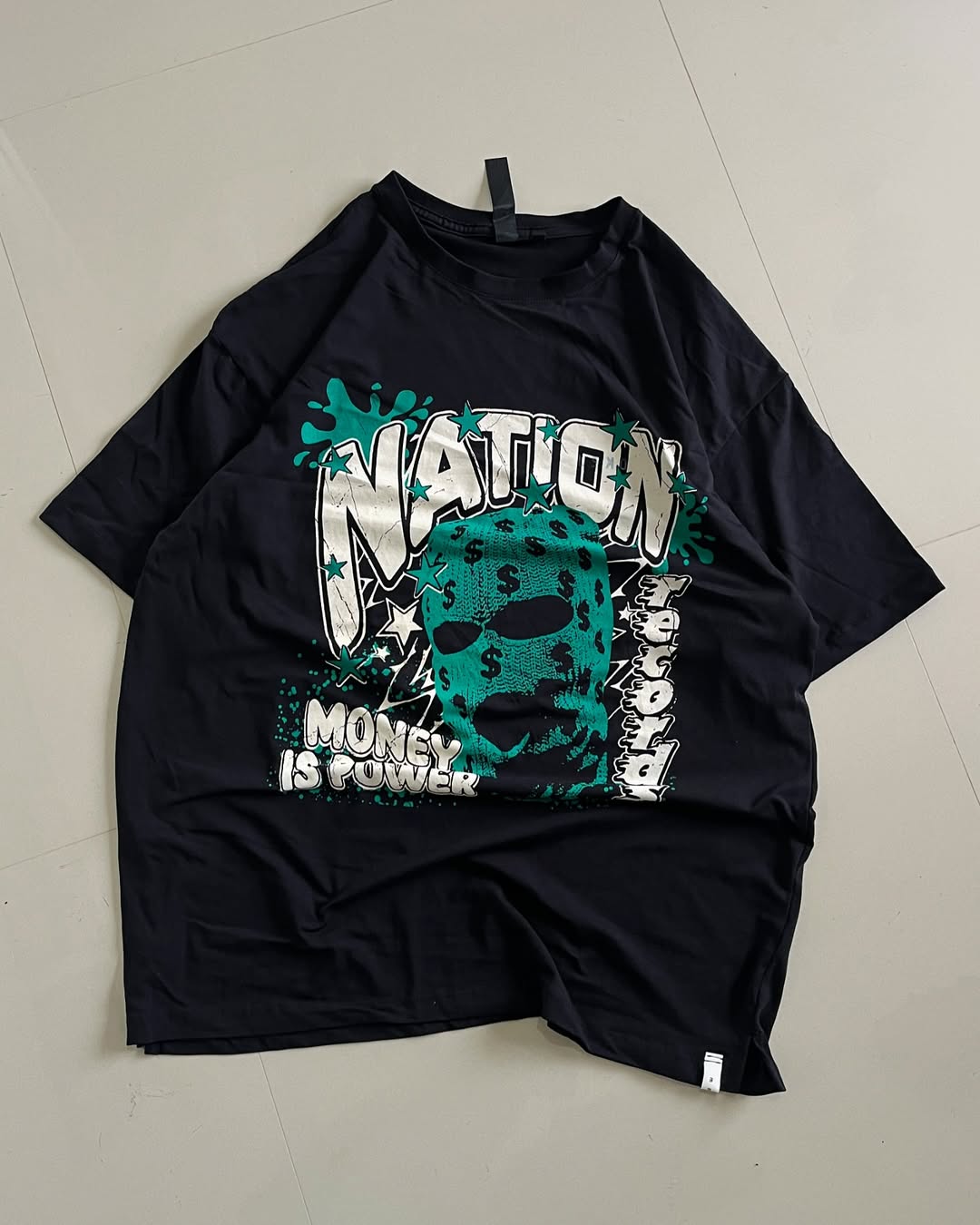 Black oversized graphic tee featuring a teal balaclava mask with dollar signs and bold “NATION” and “MONEY IS POWER” text

