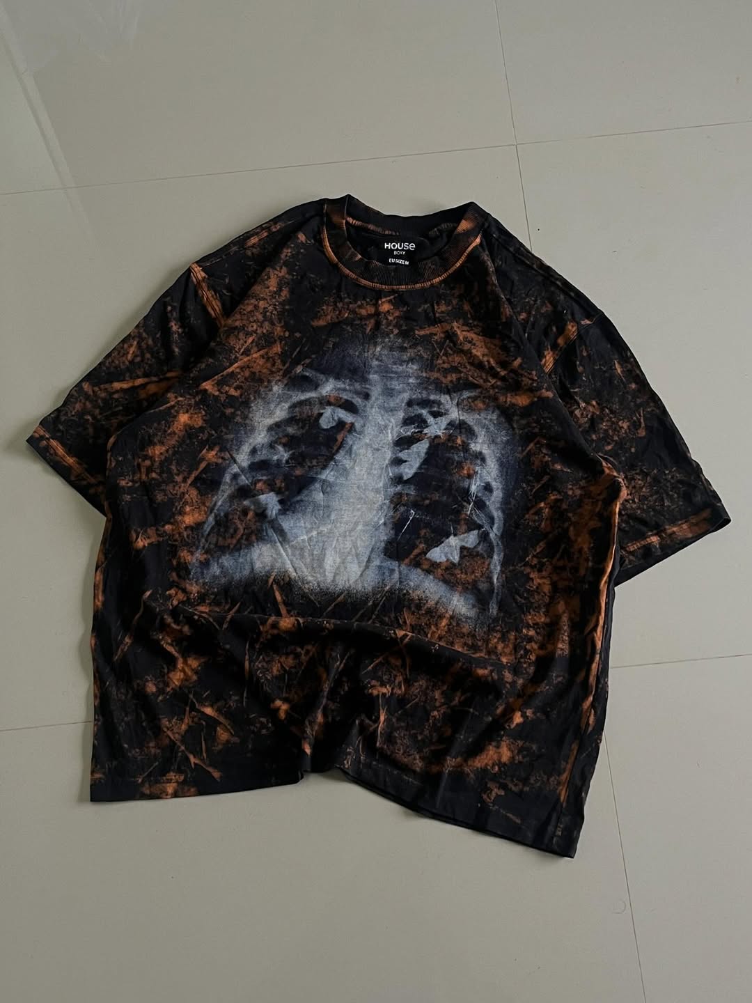 JUNKFITS oversized black tee with bleach tie-dye and ribcage x-ray graphic, front view