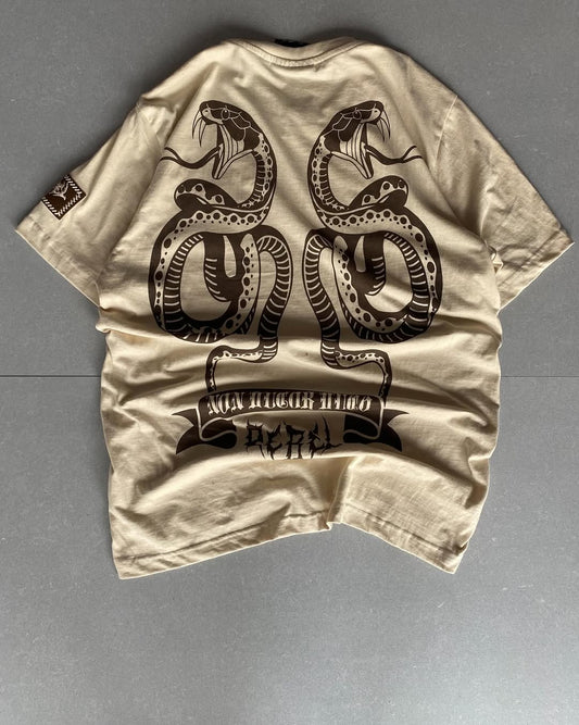Back view of JunkFits cream t-shirt featuring twin cobra snake design and "Not Built to Fear" gothic banner