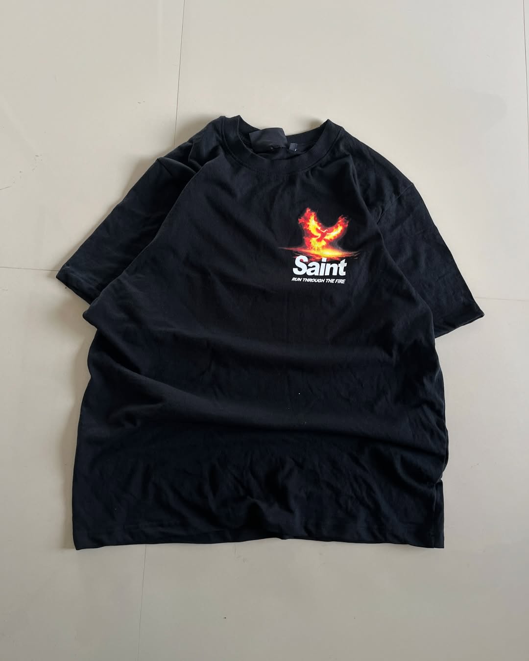 Front view of black oversized Saint tee with Formula 1 car and fiery phoenix graphic, text “Run Through The Fire” by Junk Fits

